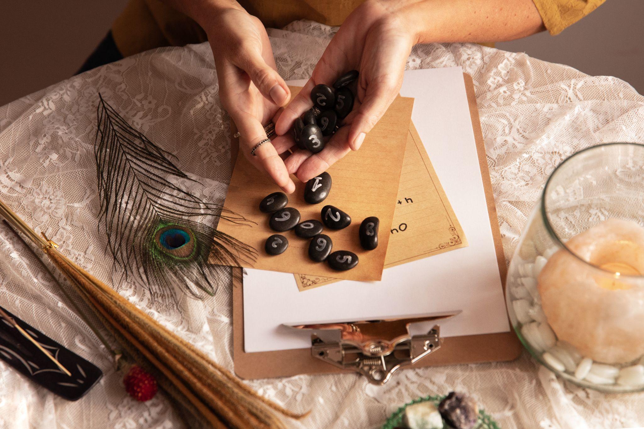 A fortune-teller's table with numbered divination stones, a peacock feather, and a lit candle