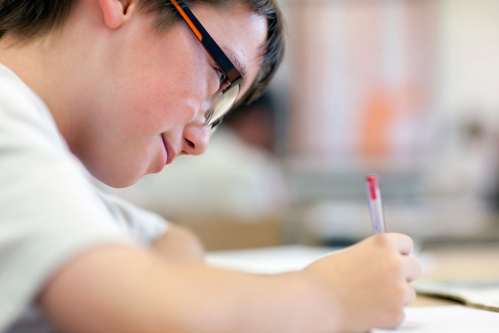 A student writing a history essay by hand at a desk